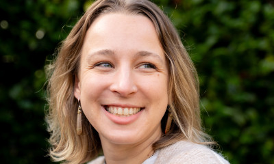 A smiling woman with sandy blond hair and a tan cardigan