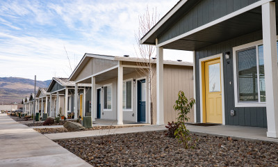 Row of cottages with low-incline, accessible ramps to the front doors. Arid hills are visible beyond this neighborhood.