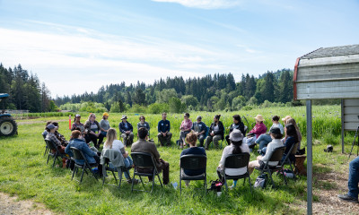 A group of people sitting in a circle in a field