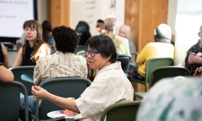 A person gestures while talking in a discussion group in a crowded room