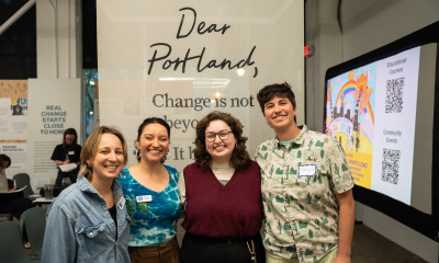 A group of four smiling people in front of a sign that says, "Dear Portland"