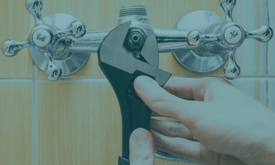 Hands holding a wrench, tightening a partially-disassembled faucet