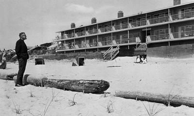 A man standing on a beach, glaring at a hotel