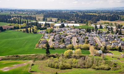 Aerial view of a compact city with strong urban growth boundaries, surrounded by green farmland and dense forests
