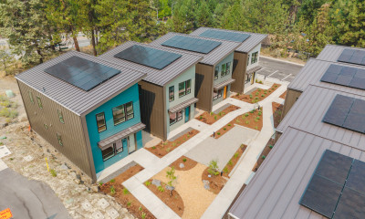 A cluster of small homes with solar panels on the roofs, in a wooded area