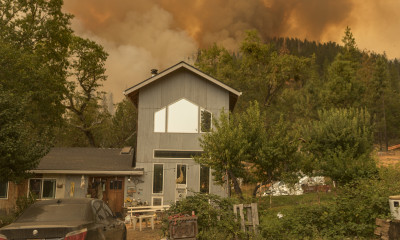 Orange light and flames rise above a home surrounded by trees