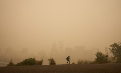 A person walking through a orange-haze-filled cityscape (Portland waterfront viewed from the east side of the river)