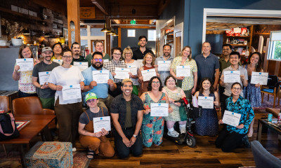 A smiling group of more than 30 people, most of whom are holding up certificates (LULI graduation)